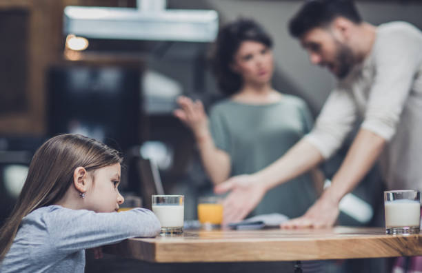 little girl feeling sad while her parents are arguing in the background.